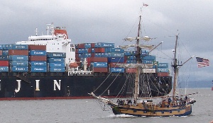 A tall ship and a big ship in the Columbia River channel.